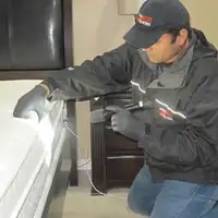 Bed bug inspection technician checking a mattress and bed frame for signs of infestation in Cleveland, OH