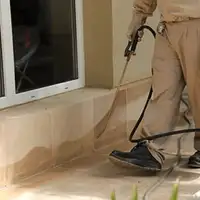 General pest control technician spraying exterior perimeter around a home in Cleveland, OH