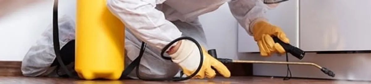 Roach exterminator treating cracks and crevices along kitchen baseboards in Cleveland, OH