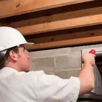 Termite inspection technician checking a basement wall and framing for termite activity in Cleveland, OH